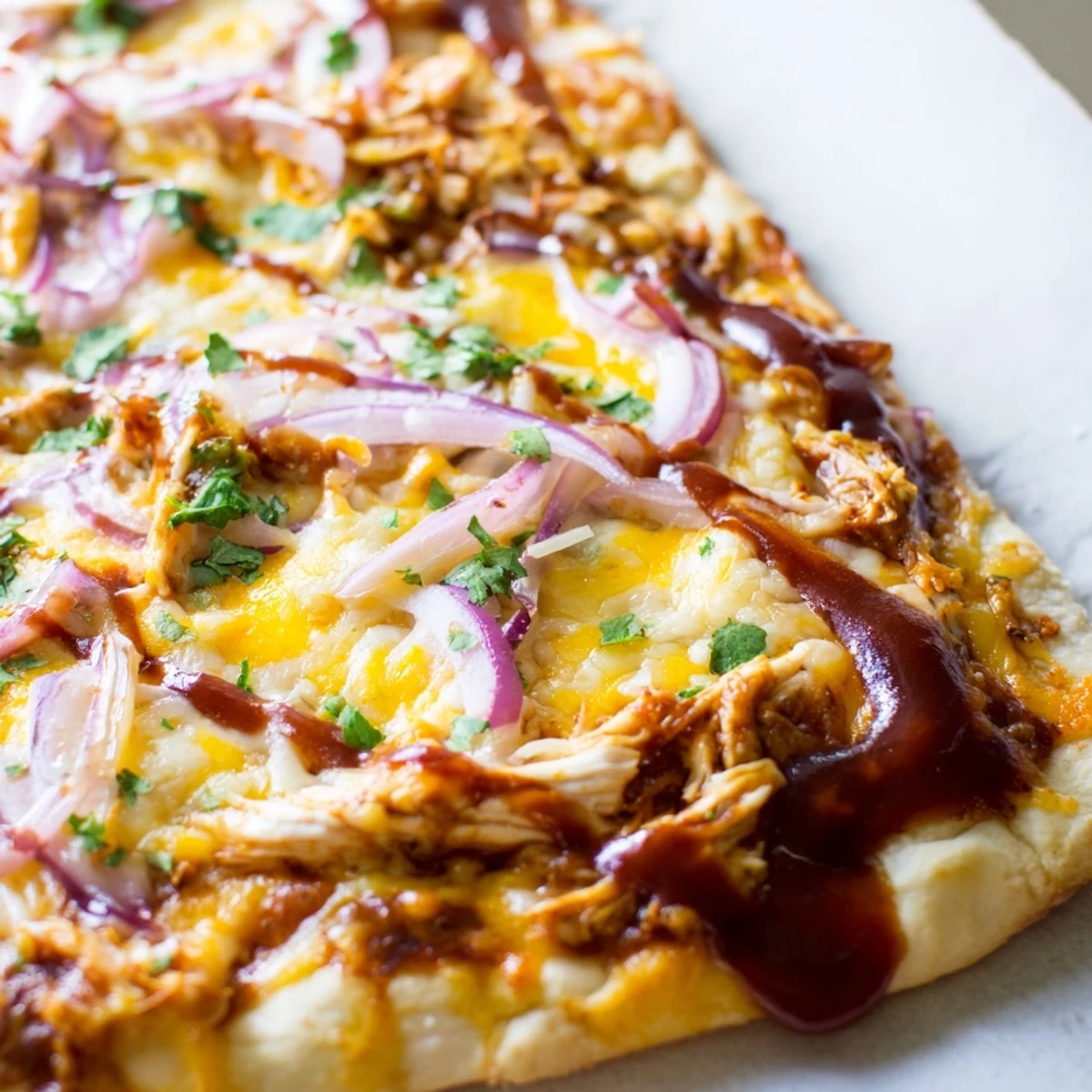 A close-up slice of Game Day BBQ Chicken Pizza shows smoky gouda, bright red onion, and fresh cilantro on a crispy crust.  