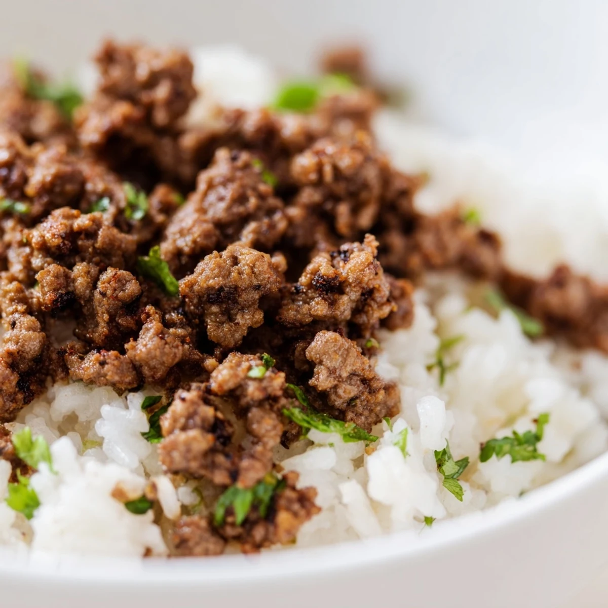 Seasoned ground beef and fluffy cilantro lime rice create these hearty Beef Burrito Bowls, topped with sour cream, cheese, and cherry tomatoes.