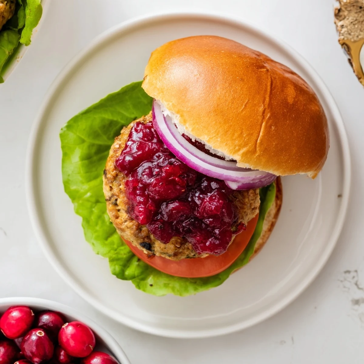 Golden-brown Turkey Burgers with Cranberry Sauce rest on toasted buns with fresh lettuce and tomato.