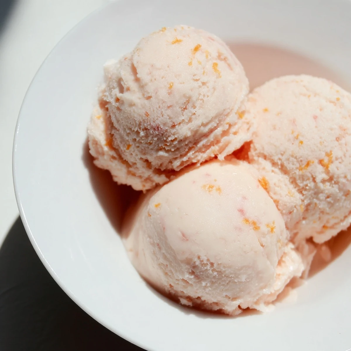 Vibrant Pink Grapefruit Sorbet in a chilled bowl, topped with fresh mint and zest.