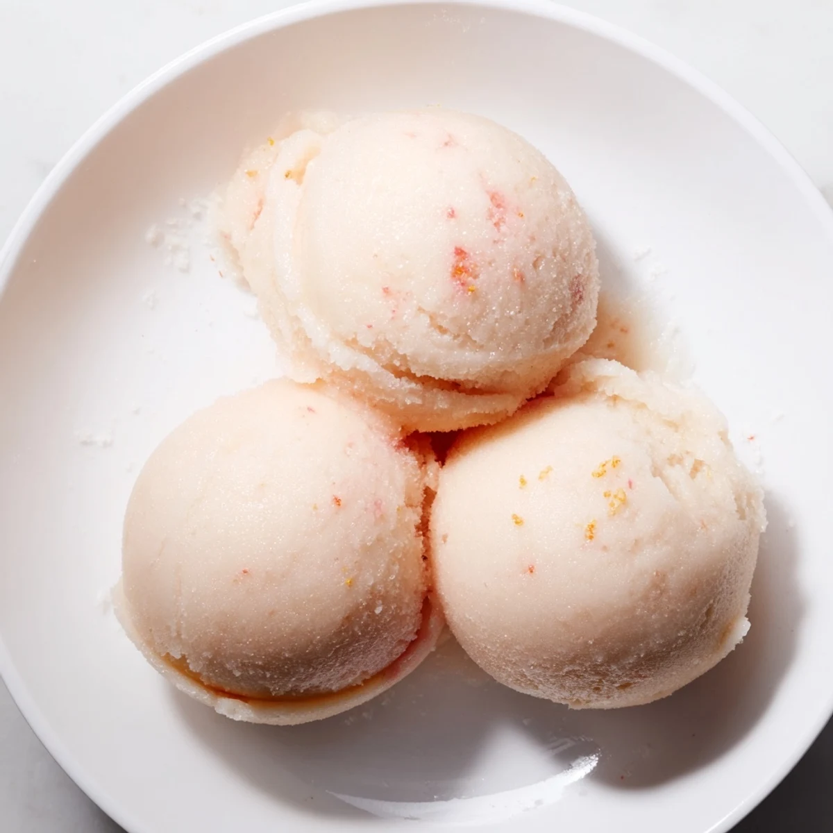 Serving Pink Grapefruit Sorbet in a clear glass, showing its bright, slushy texture.