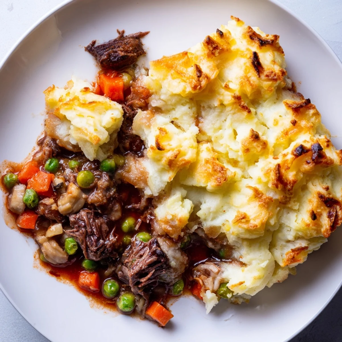 Rustic casserole dish of Shepherd's Pie, featuring creamy mashed potatoes browned with parmesan and fresh herbs.