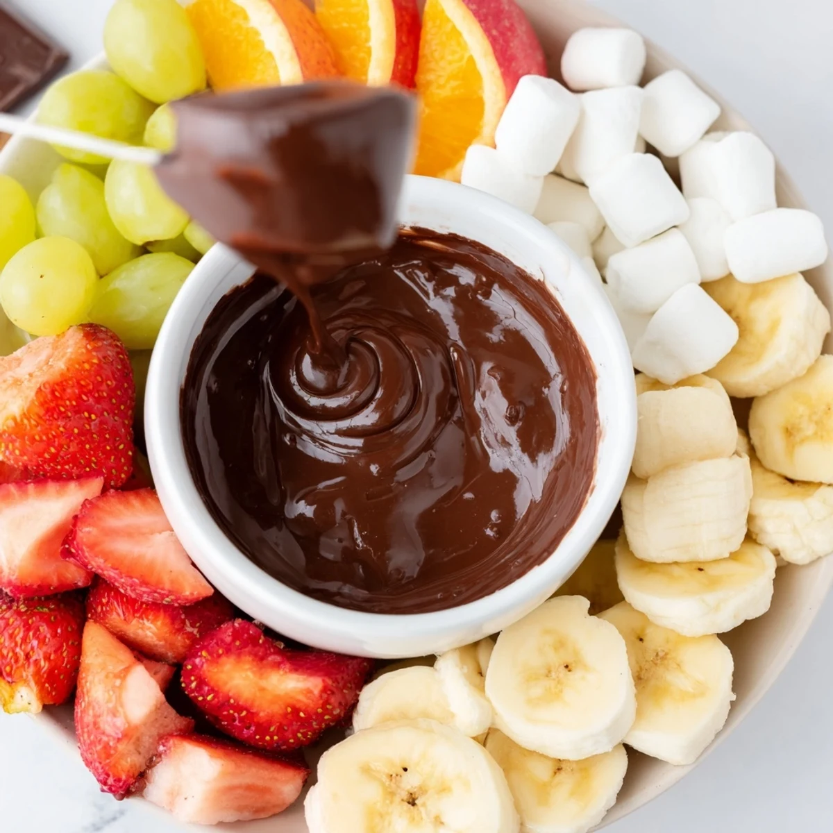 Close-up of Romantic Chocolate Fondue with Marshmallows and Fruit, showing rich glossy chocolate and juicy apple slices ready to be dipped.