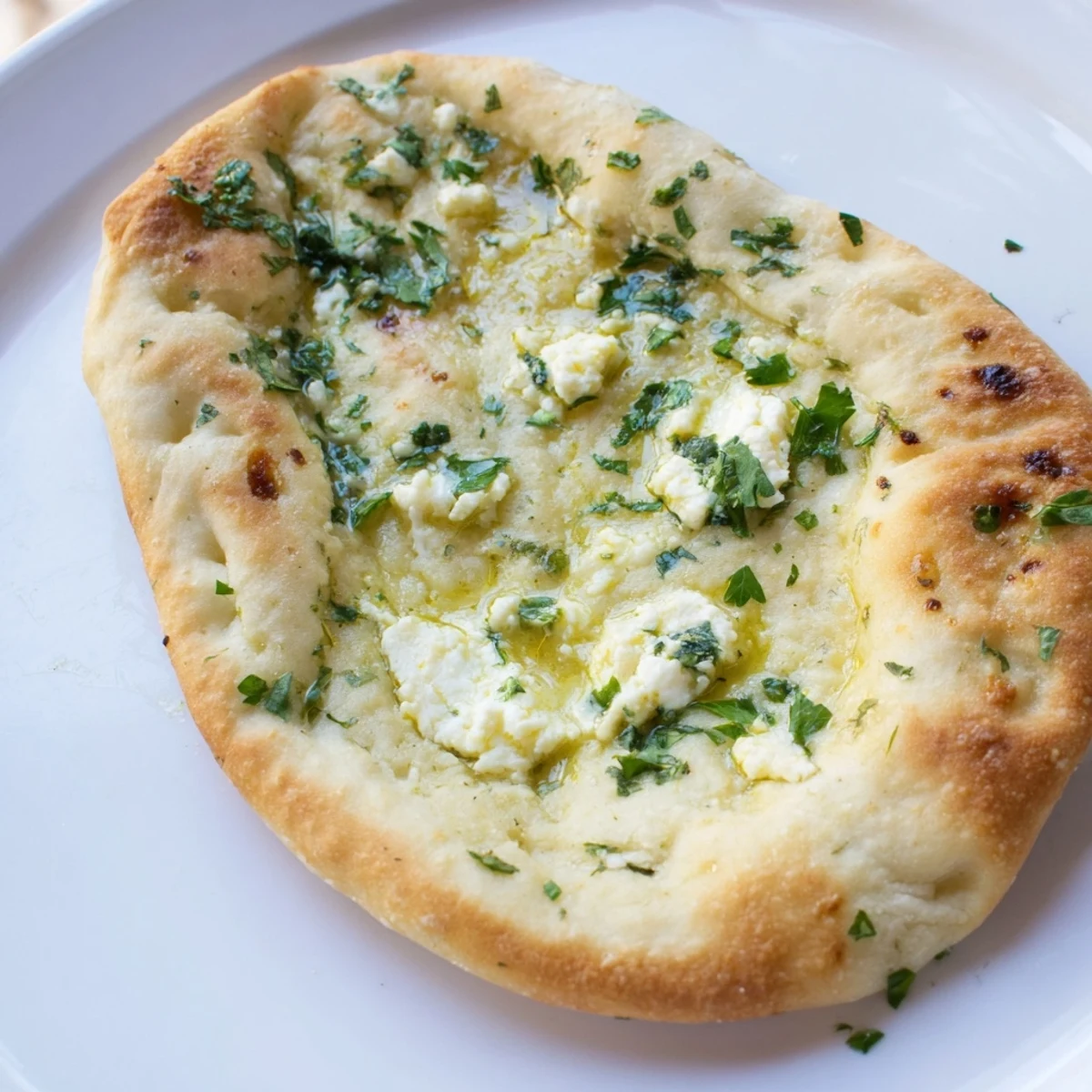 Fluffy Cottage Cheese Garlic Naan stuffed with creamy cheese, served alongside a steaming bowl of curry.