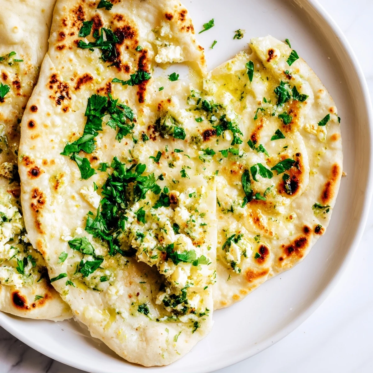 Homemade Cottage Cheese Garlic Naan with visible herbs, perfect for tearing and dipping into a flavorful sauce.