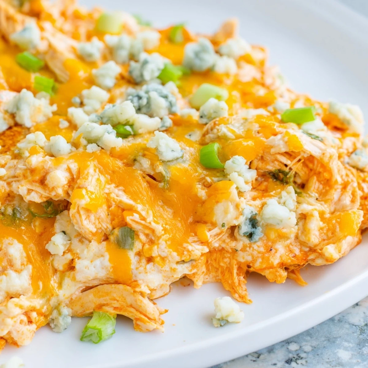 Keto Buffalo Chicken Dip served warm in a dish, with celery sticks and a drizzle of extra buffalo sauce.
