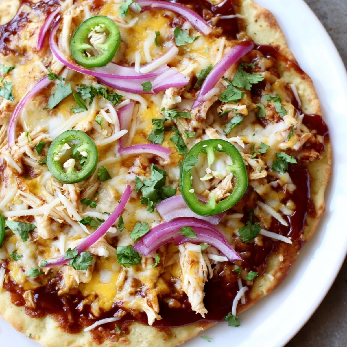 Golden BBQ Chicken Flatbread with melted mozzarella and cheddar, topped with red onions and fresh cilantro on a baking sheet.