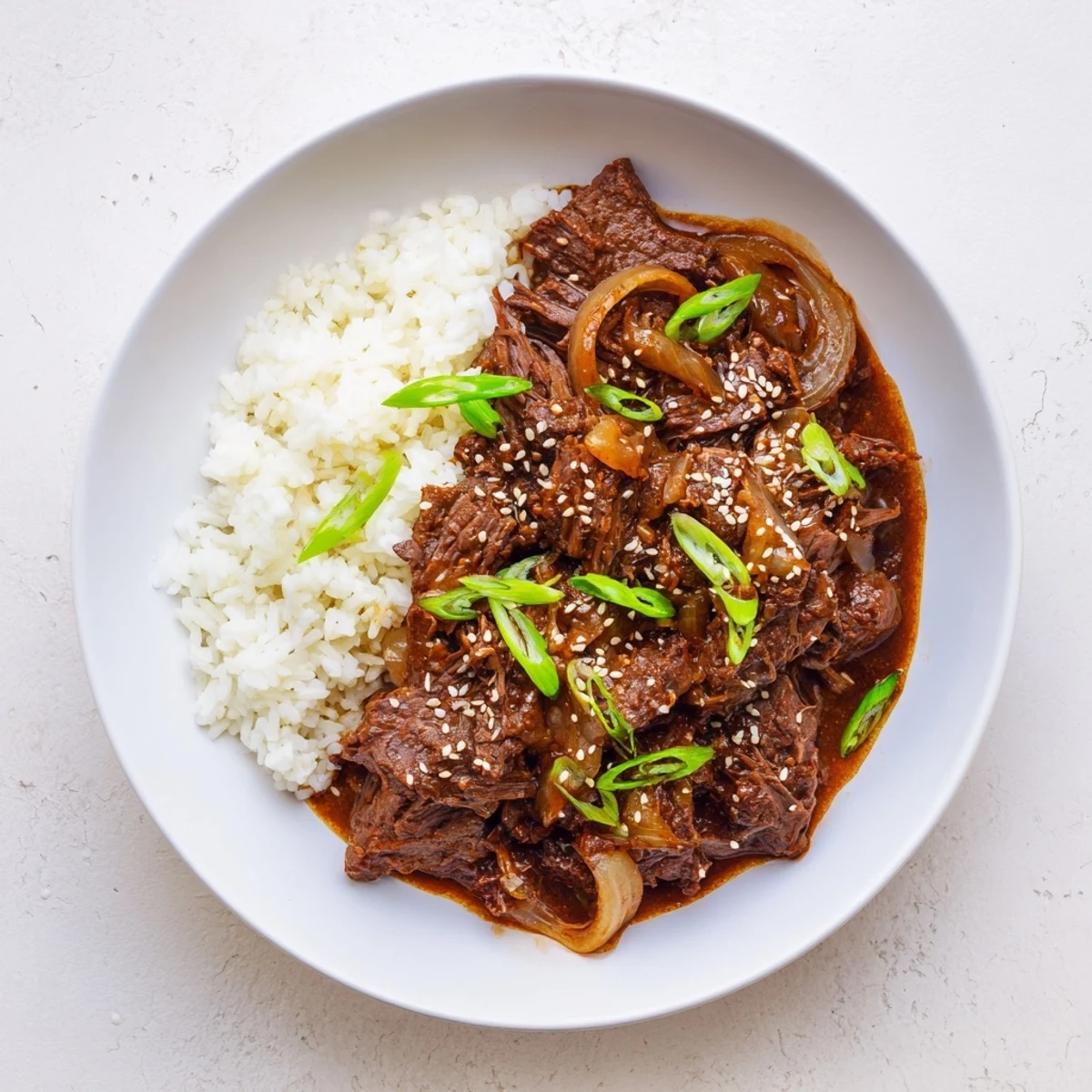 Crock Pot Korean Beef simmering in a rich, glossy sauce with tender shredded beef and sliced onions.