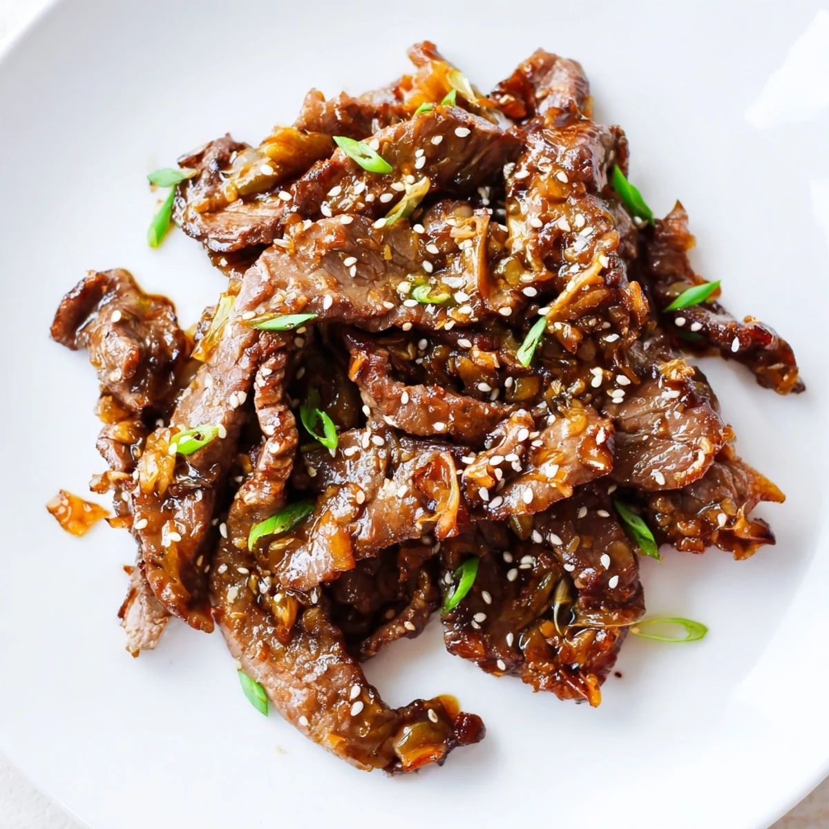 Melt-in-your-mouth slow cooker Mongolian Beef served in a savory-sweet sauce with sesame garnish.