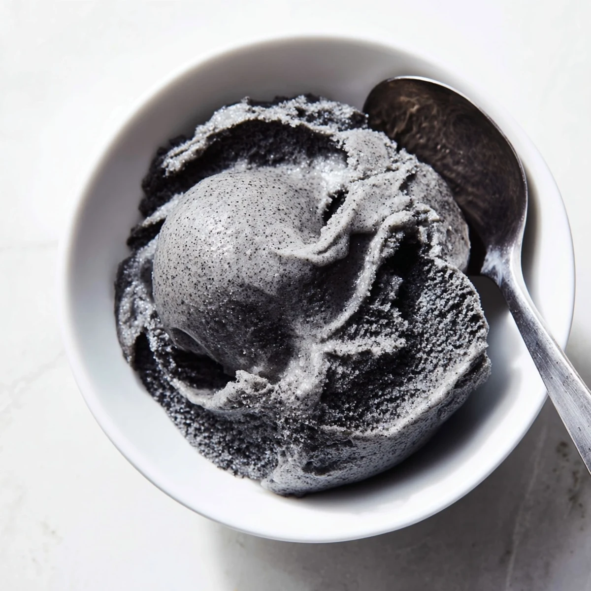 Scoops of rich black sesame ice cream served in a waffle cone with a drizzle.