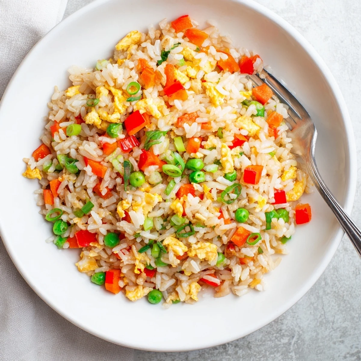 Sizzling Fried Rice with peas, carrots, and bell peppers served steaming hot in a ceramic bowl.