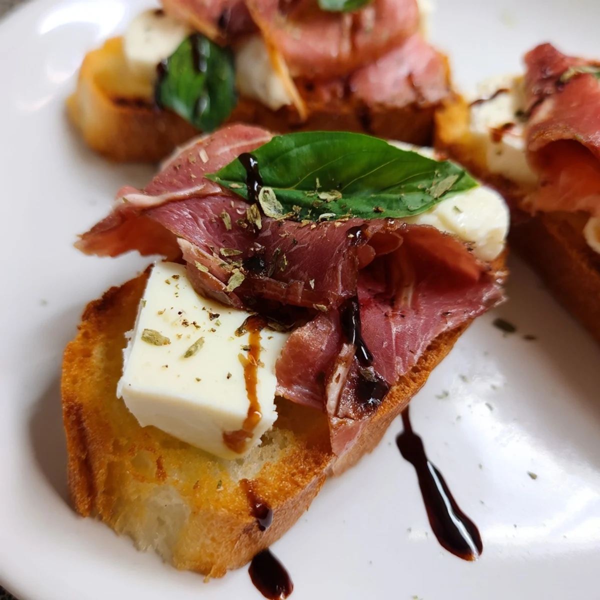 Crispy baguette crostini topped with melted mozzarella, roast beef, and a ribbon of fresh basil, finished with balsamic glaze.