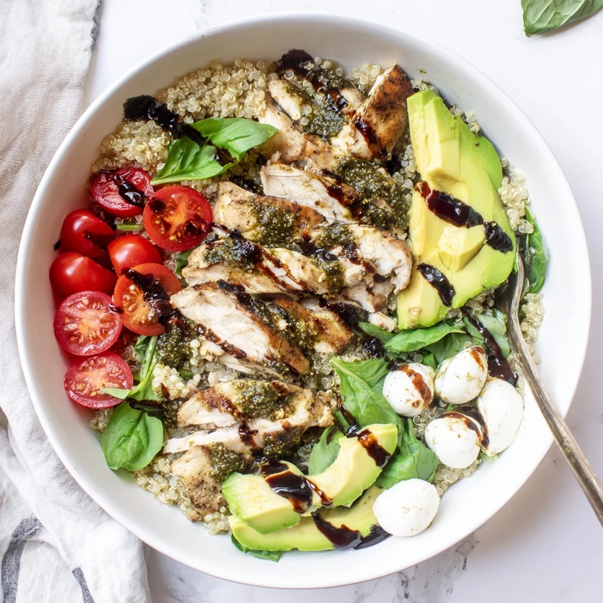 Close-up of Pesto Chicken Caprese Grain Bowl topped with tomatoes, basil, and avocado.