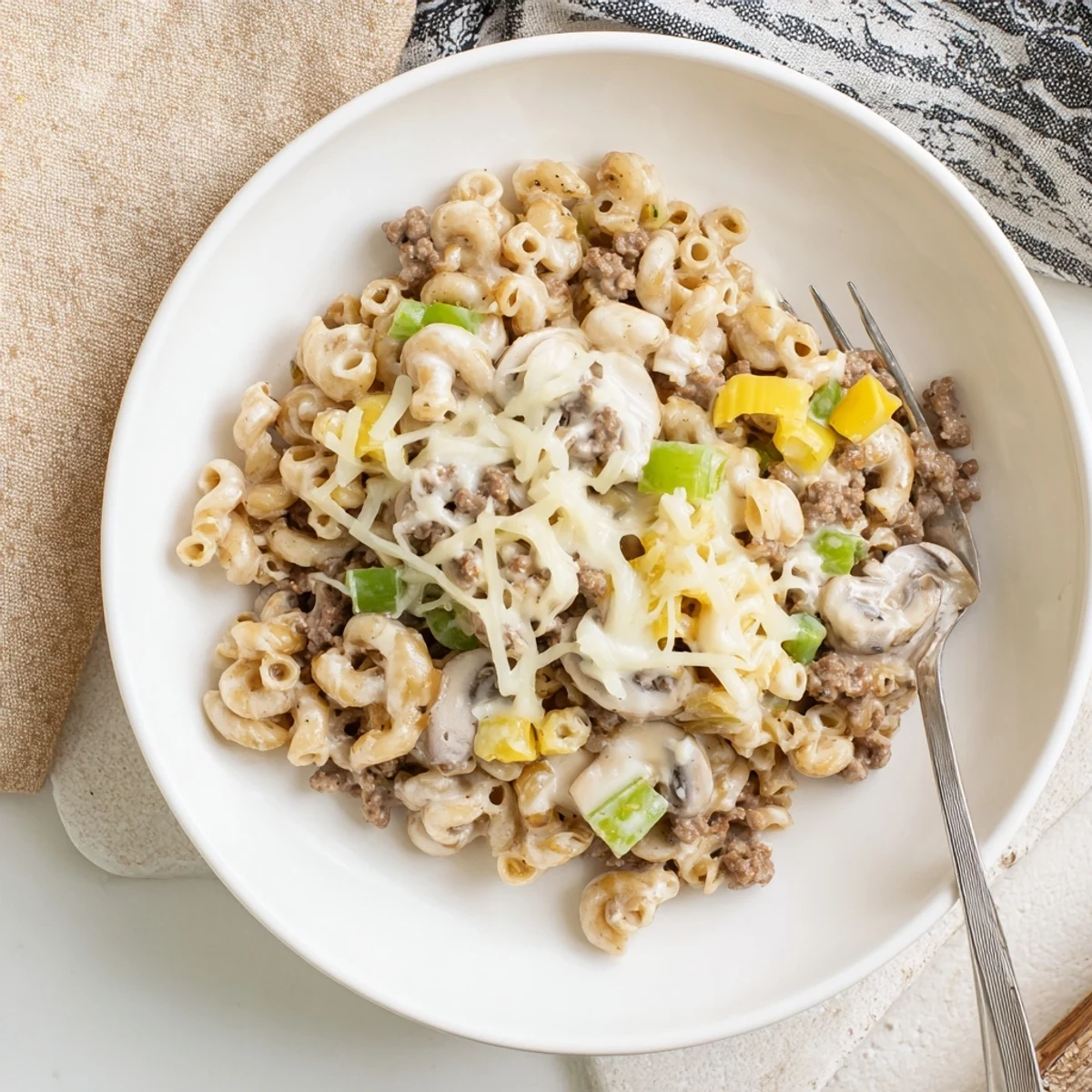 Easy High Protein Philly Cheesesteak Mac served hot in a skillet, with diced bell peppers and onions visible.