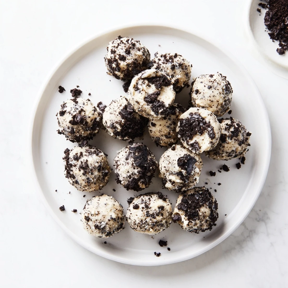 A close-up of Cream Cheese Oreo Protein Balls on a marble slab, with Oreo crumbs and a chocolate drizzle for a sweet finish.
