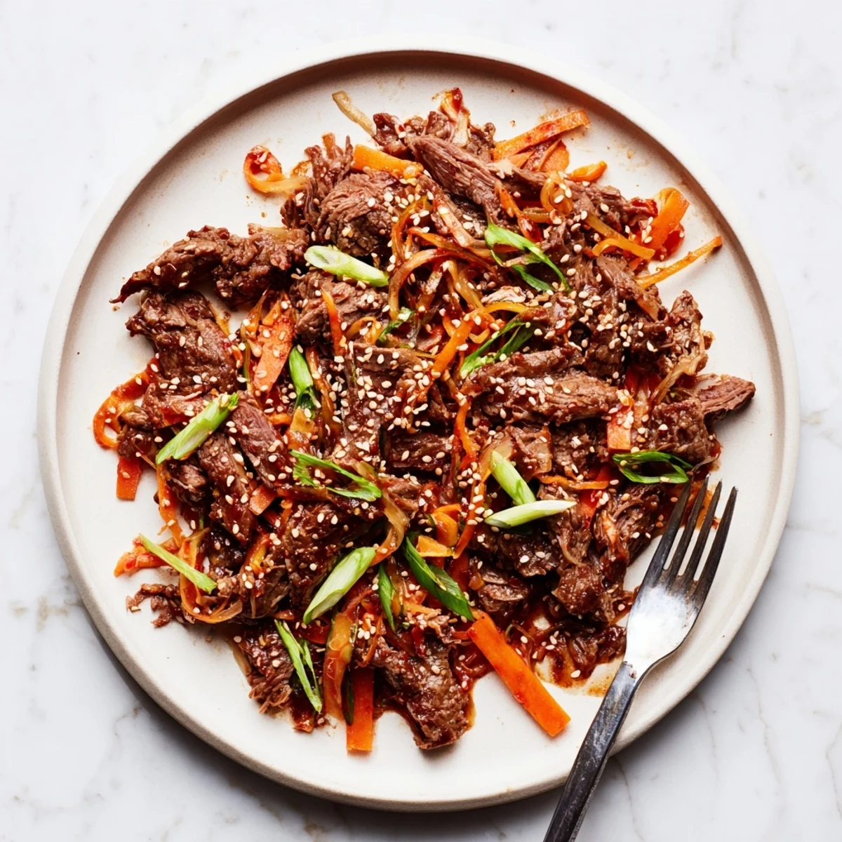 A close-up of Korean Style Pot Roast with tender shredded beef in a glossy, savory-sweet sauce, garnished with sesame seeds and scallions.