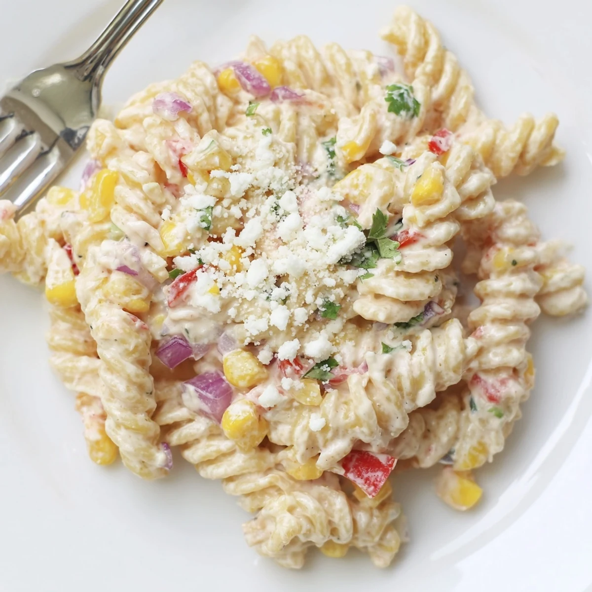 Colorful Mexican street corn pasta salad featuring golden corn, peppers, and creamy cotija cheese in a smoky lime dressing