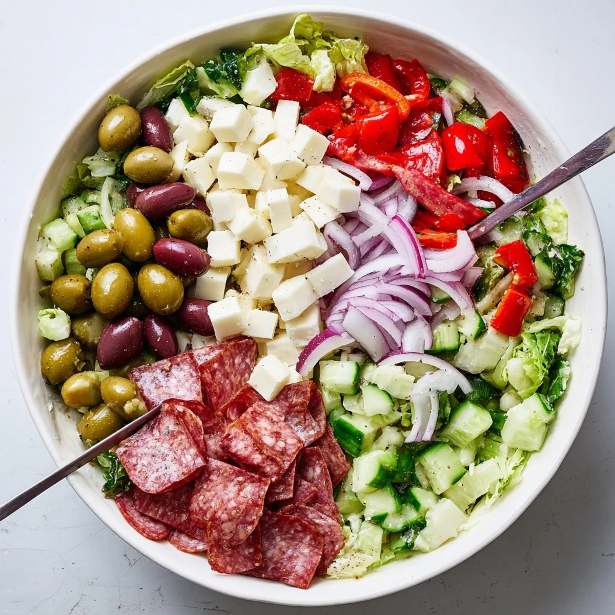 Colorful Italian chopped salad with fresh romaine, salami, mozzarella, and olives drizzled with zesty homemade dressing