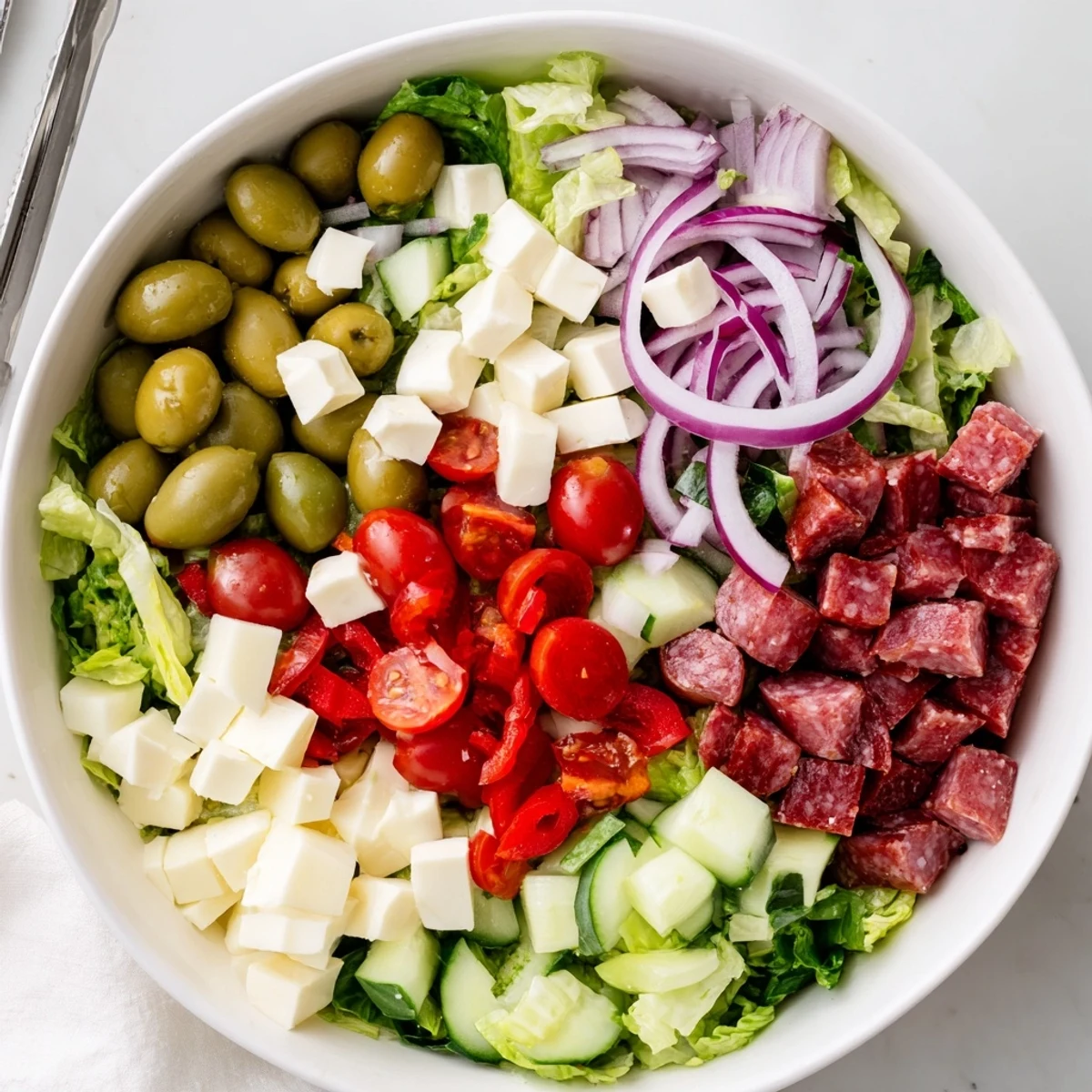Vibrant bowl of Italian chopped salad featuring crisp vegetables, cheese, and cured meats tossed in tangy dressing