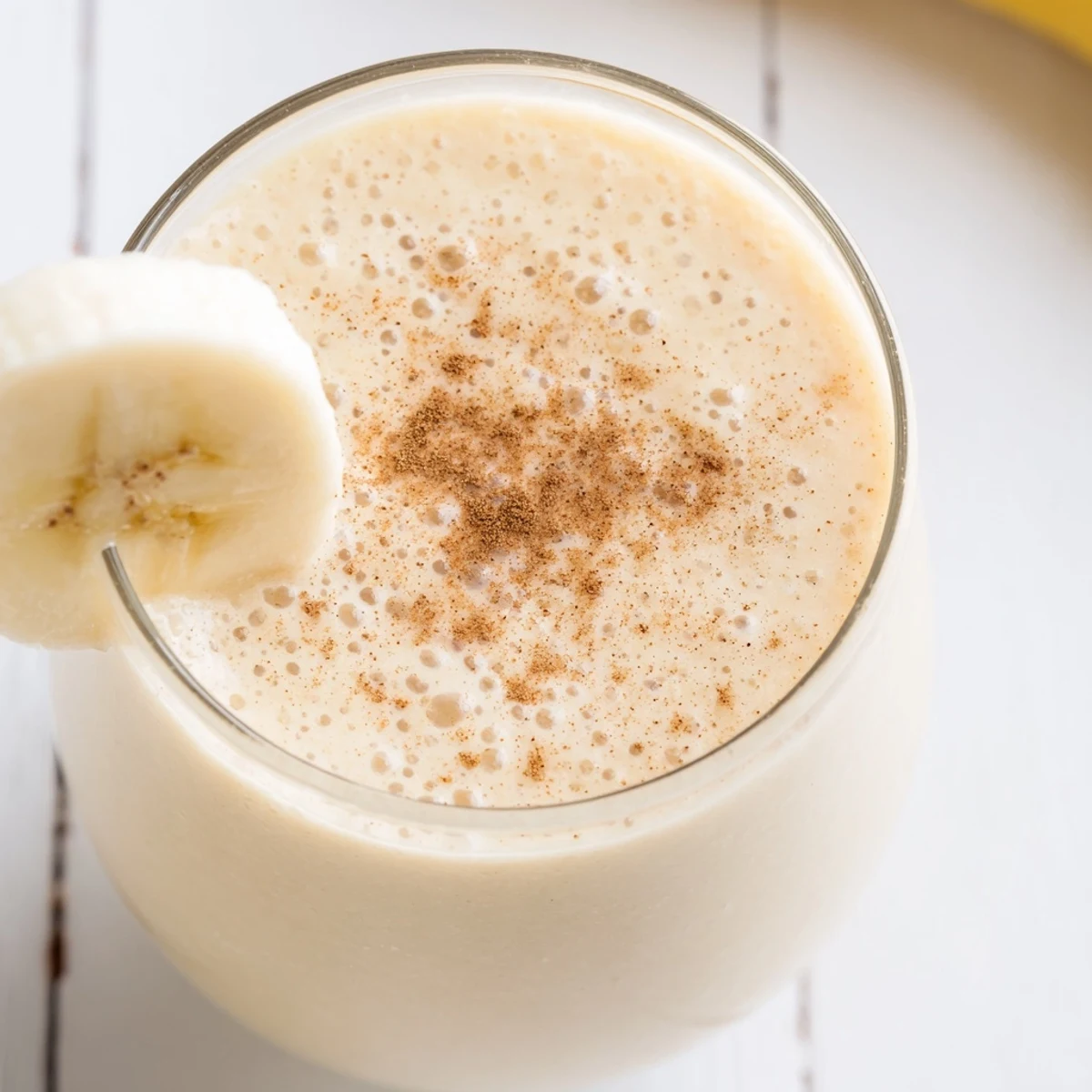 Creamy Greek yogurt banana smoothie poured into a tall glass with sliced banana garnish
