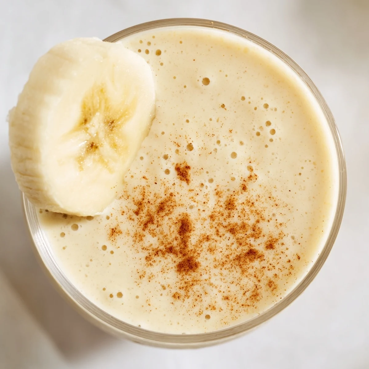 Thick protein-packed Greek yogurt banana smoothie topped with granola and chia seeds in clear glass