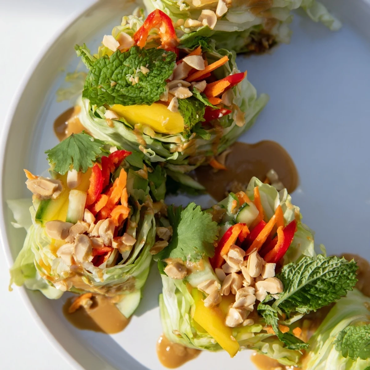 Fresh cabbage leaf wraps showcasing sweet mango strips crunchy vegetables and herbs with tangy peanut dressing