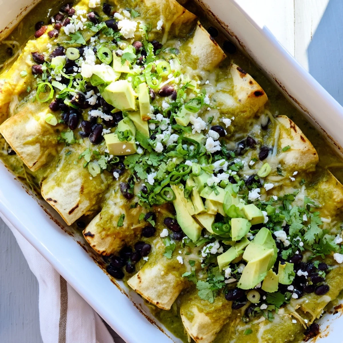 Plate of Mexican enchiladas drizzled with tangy tomatillo salsa and garnished with fresh cilantro