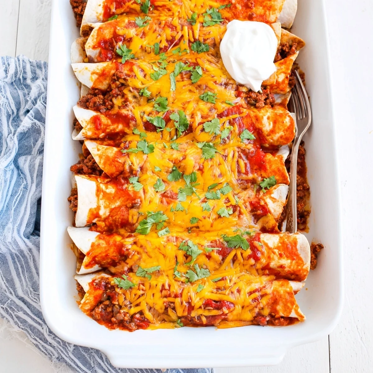 Baked savory beef enchiladas with melted cheddar and Monterey Jack cheese topping bubbling under rich red sauce