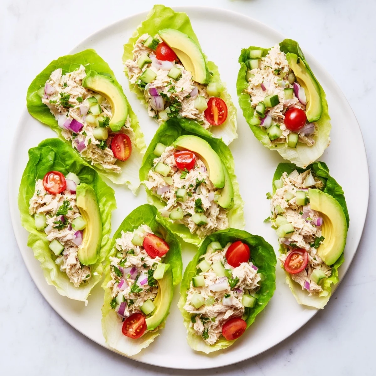 Homemade tuna salad nestled in butter lettuce leaves with diced vegetables and herbs