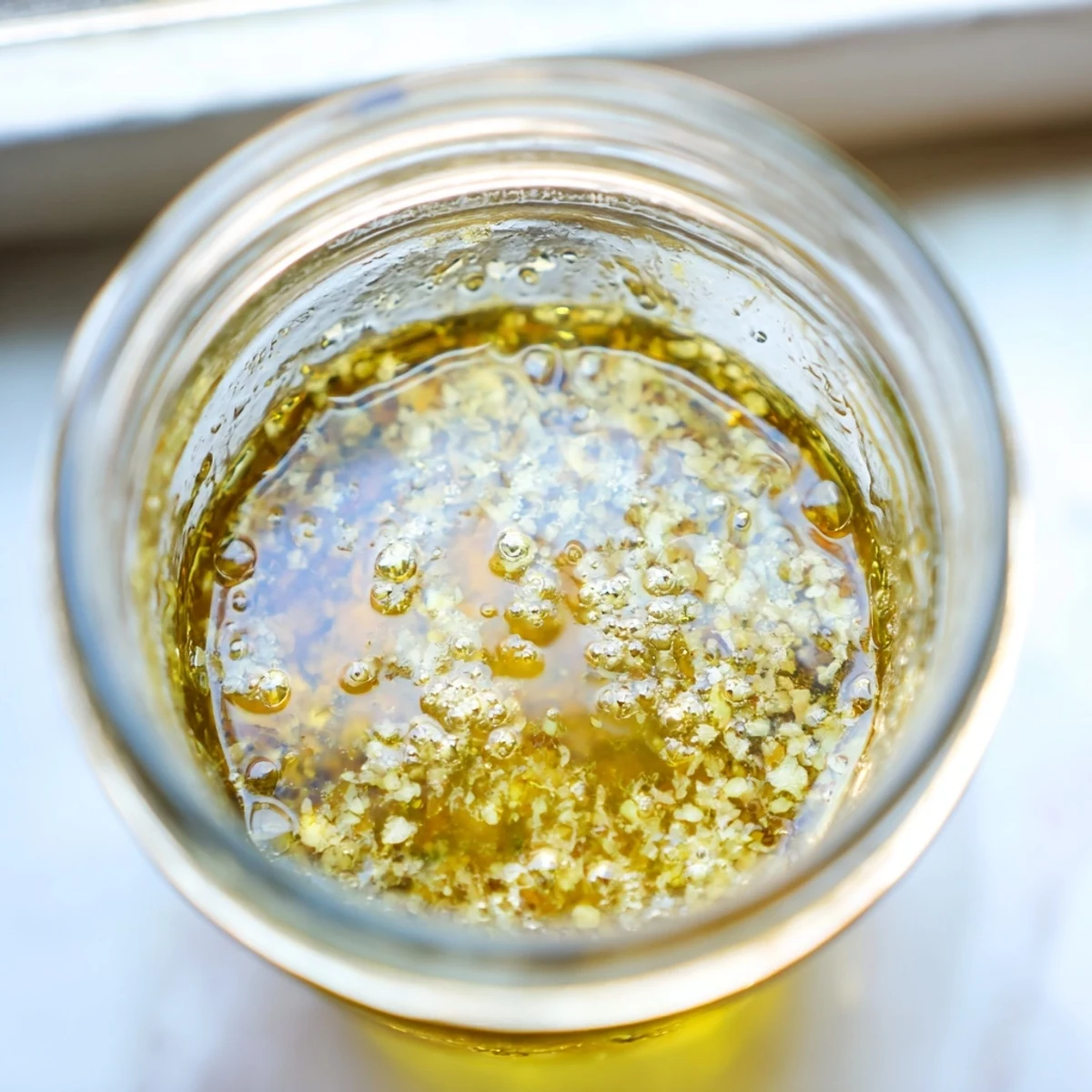 Creamy homemade easy lemon vinaigrette dressing in glass jar with olive oil and fresh herbs