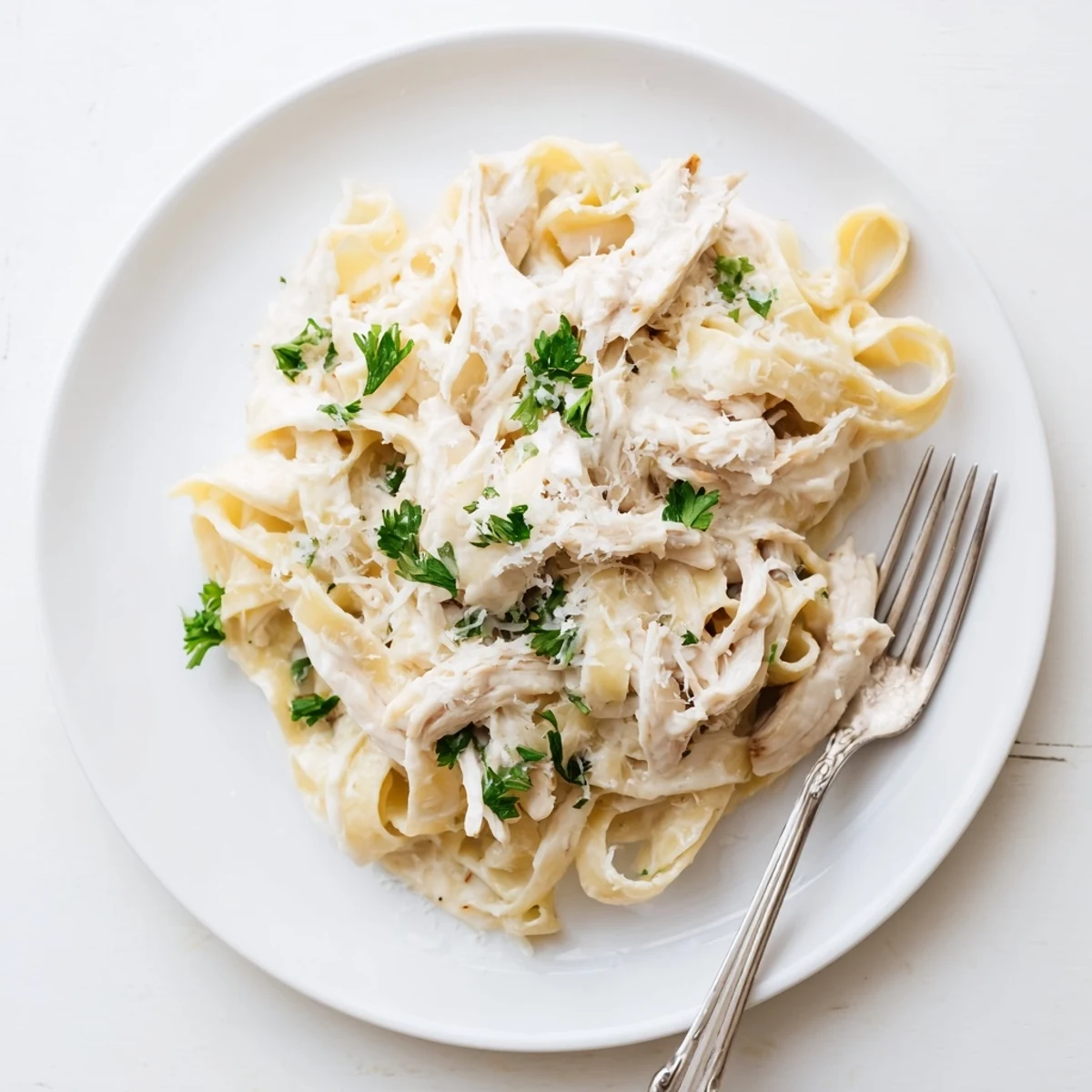 Golden slow cooker Chicken Alfredo topped with fresh parsley and parmesan cheese