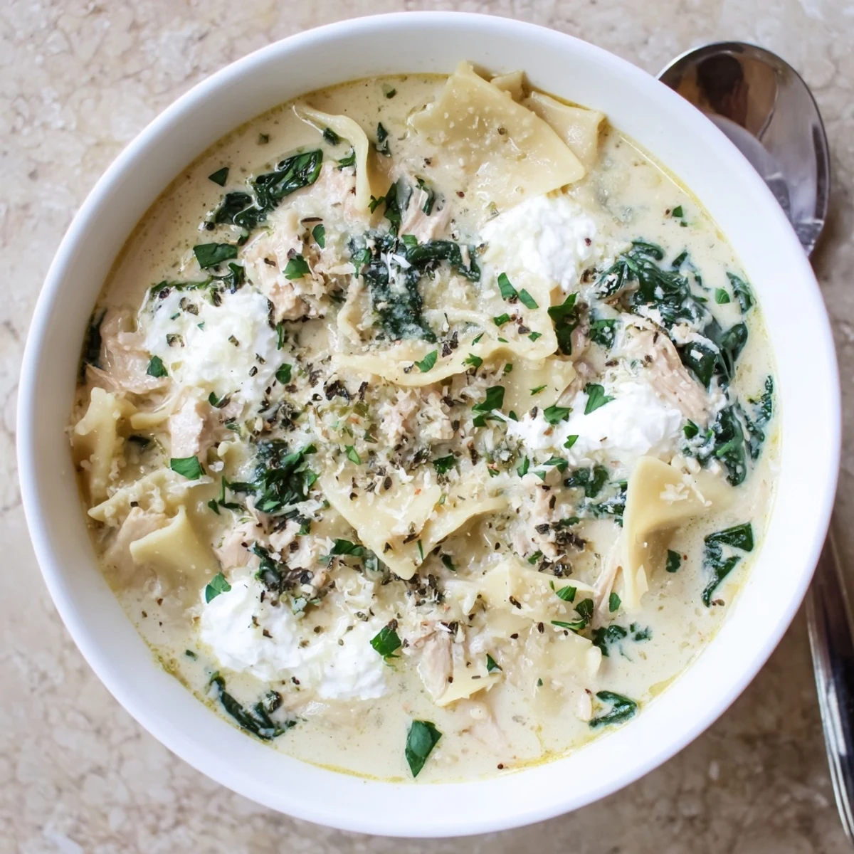 Creamy white lasagna soup with tender chicken and spinach in a savory Parmesan broth