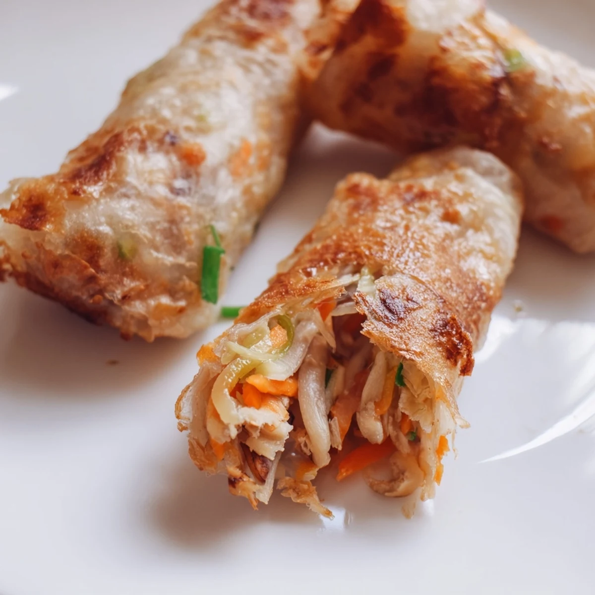 Golden crispy rice paper spring rolls with savory vegetable filling on a white plate
