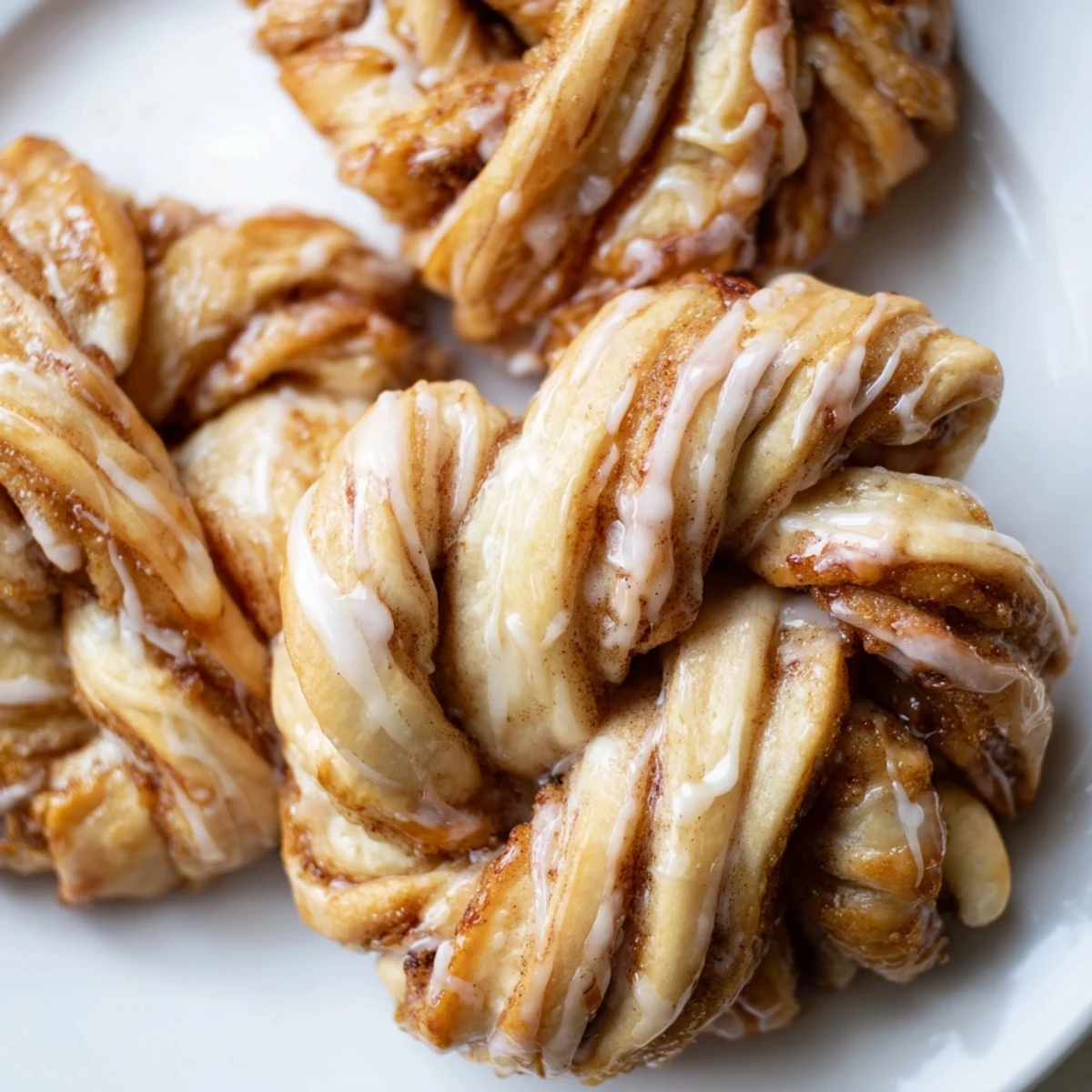 Golden sweet cinnamon twists drizzled with vanilla glaze on a rustic wooden board