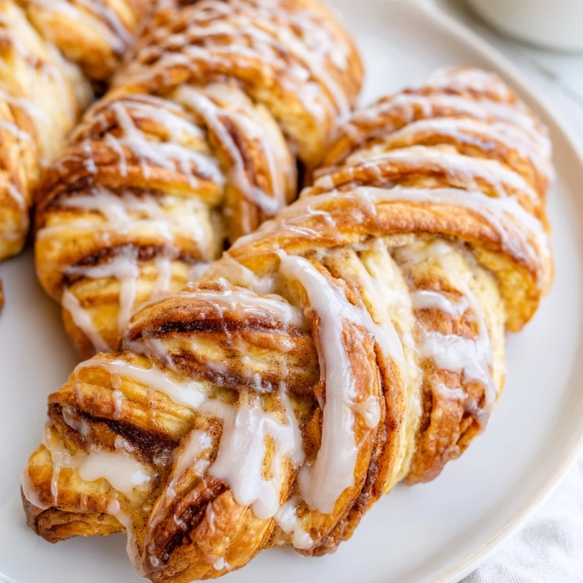 Warm sweet cinnamon twists arranged on parchment paper with sweet vanilla coating