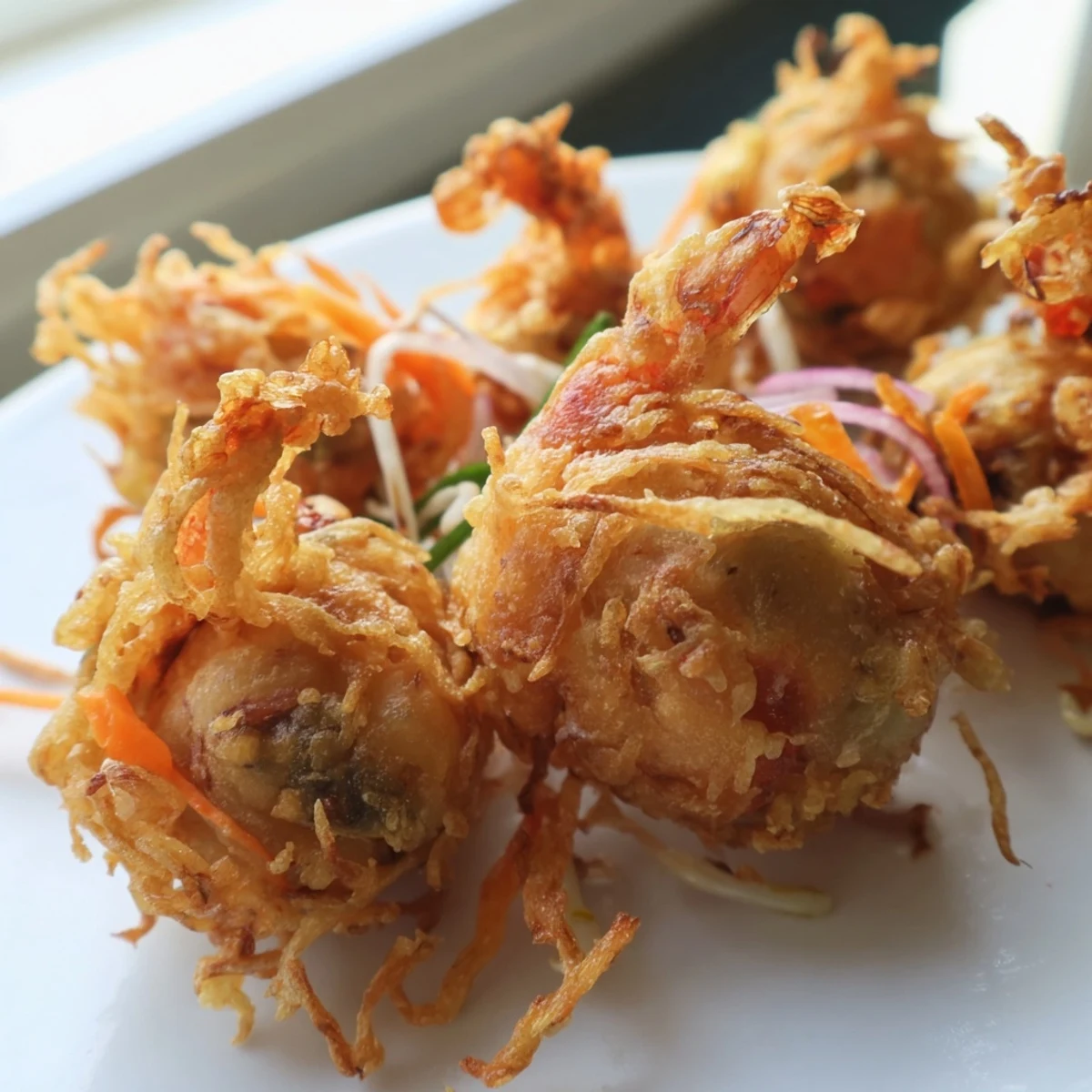 Ukoy Filipino shrimp fritters sizzling in hot oil with julienned carrots and bean sprouts