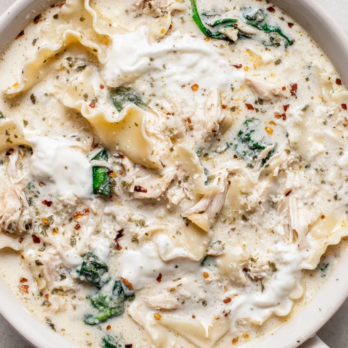 Creamy white lasagna soup with melted mozzarella and tender broken noodles in a white bowl