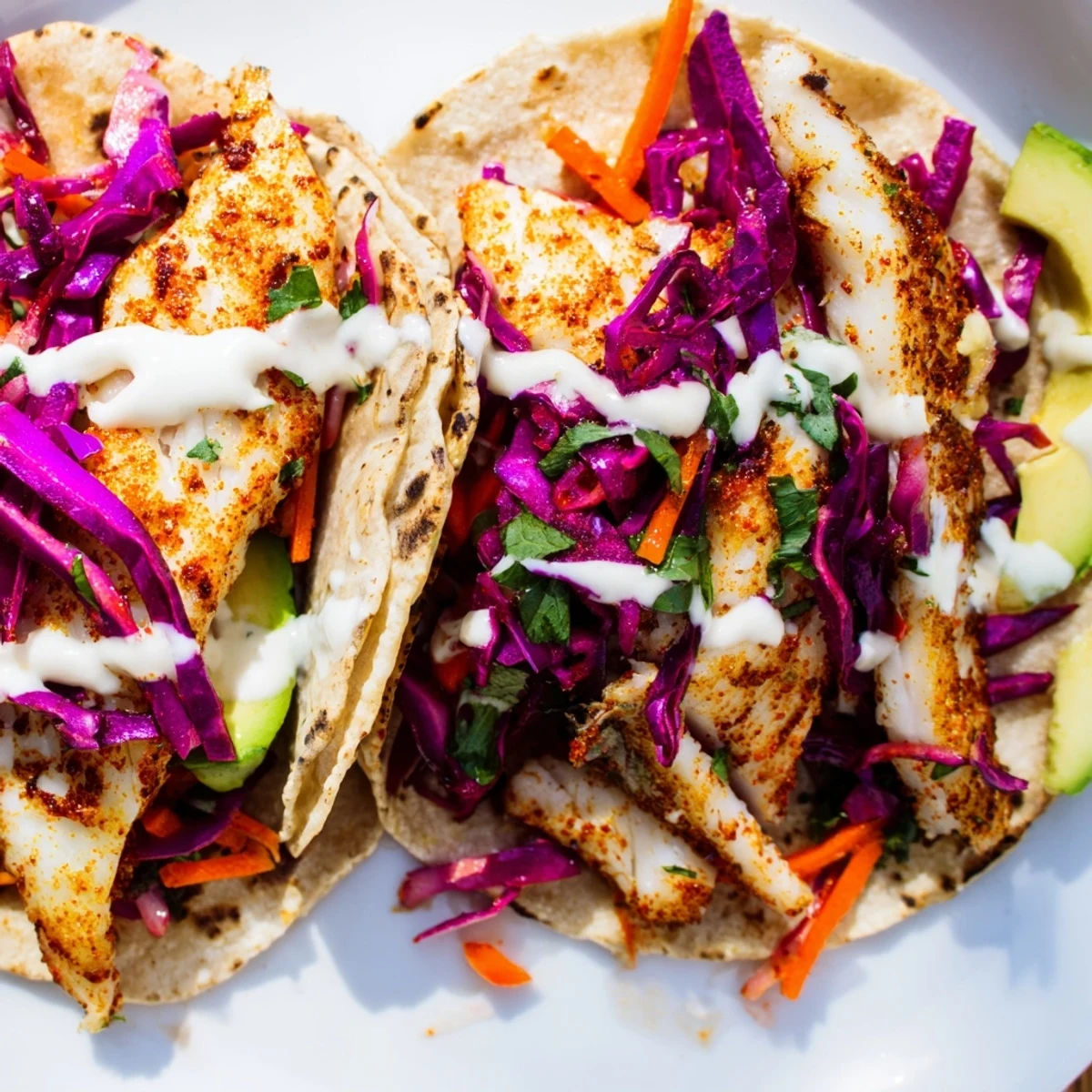 Crispy spiced tilapia fish tacos topped with vibrant cabbage slaw and creamy lime crema