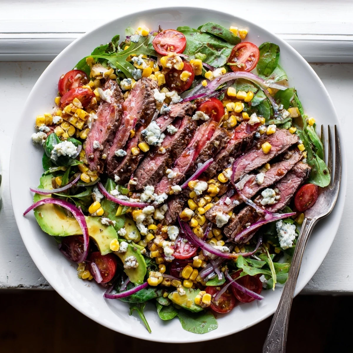 Balsamic steak Gorgonzola salad drizzled with vinaigrette and scattered with grilled corn