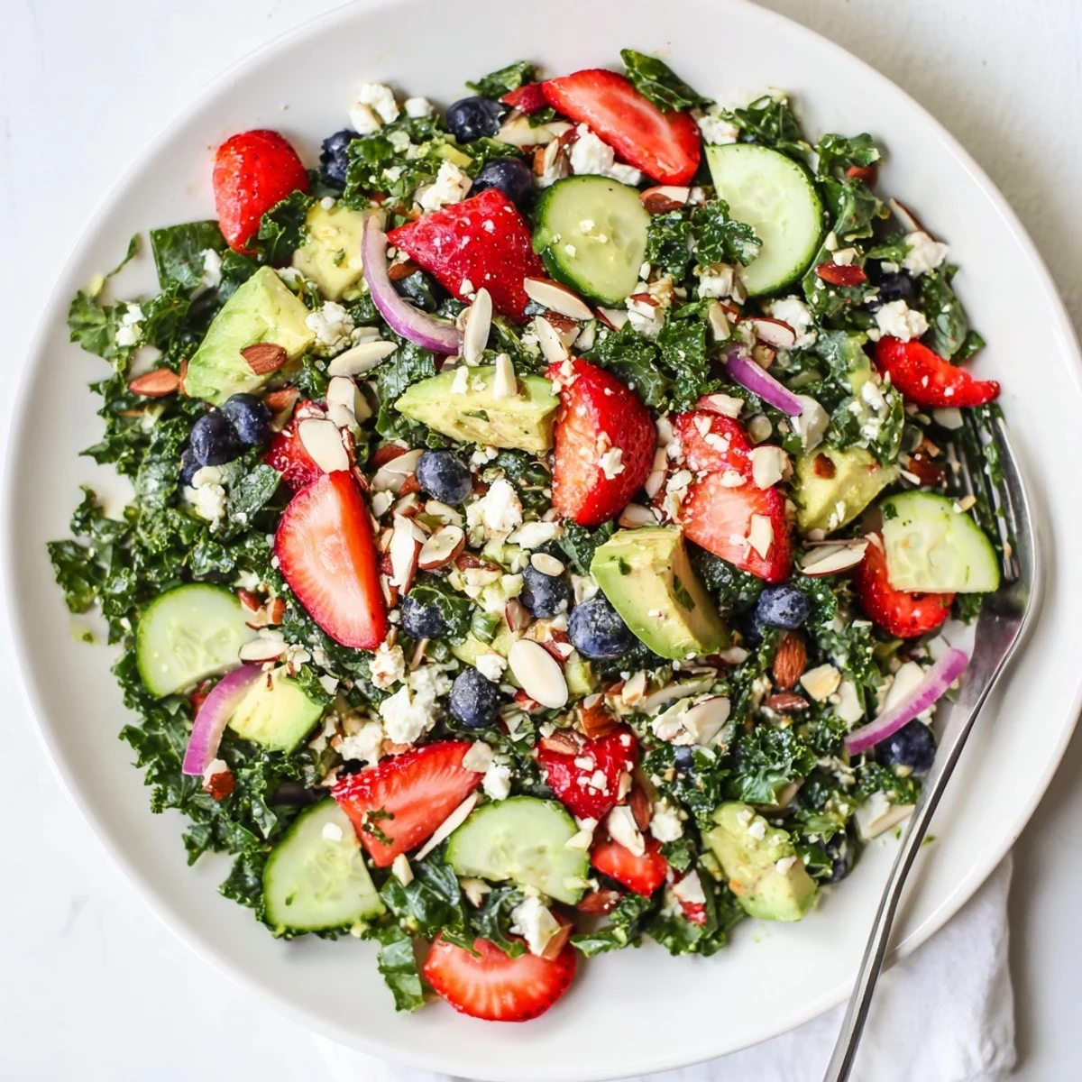 A vibrant summer kale salad topped with fresh berries, feta, and toasted almonds