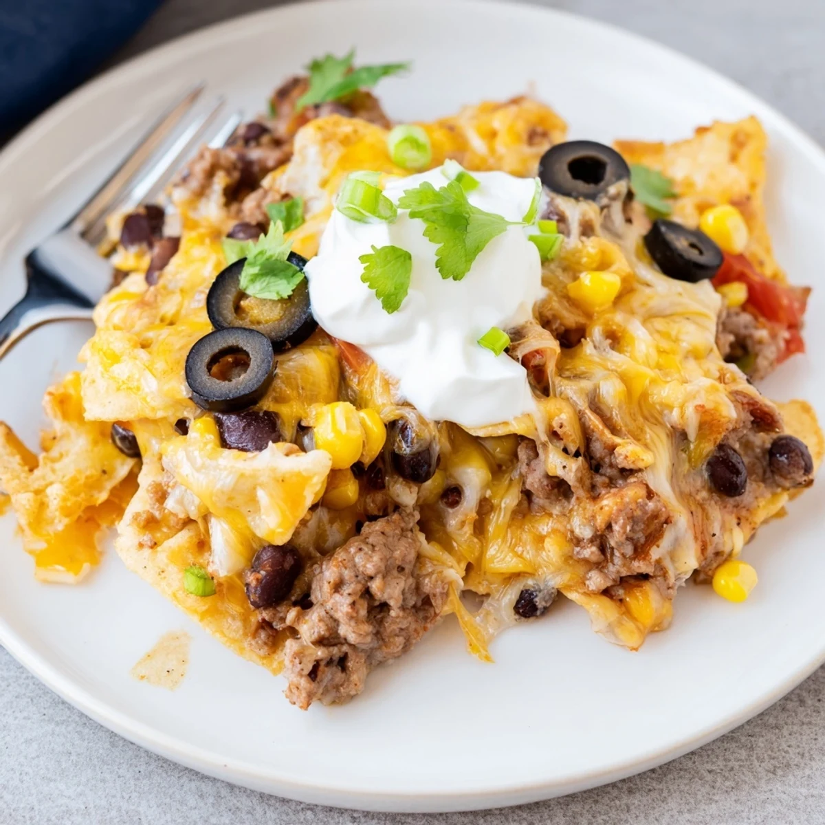 A hearty Cheesy Nacho Casserole layered with seasoned beef, jalapeños, sour cream.