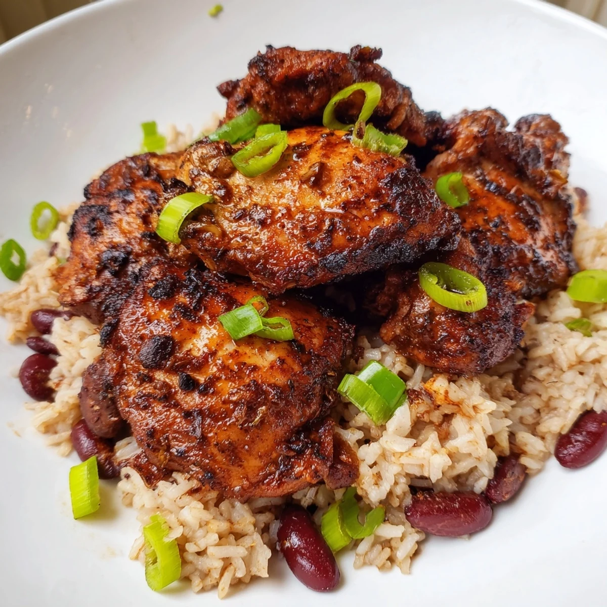 Succulent oven baked jerk chicken atop fluffy coconut kidney bean rice garnished with fresh green onions