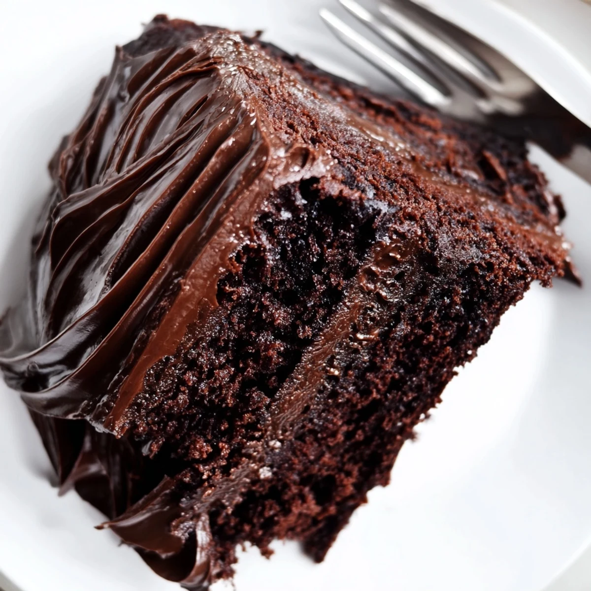 Moist Matilda chocolate cake with thick chocolate frosting and decorative swoops on a serving plate.