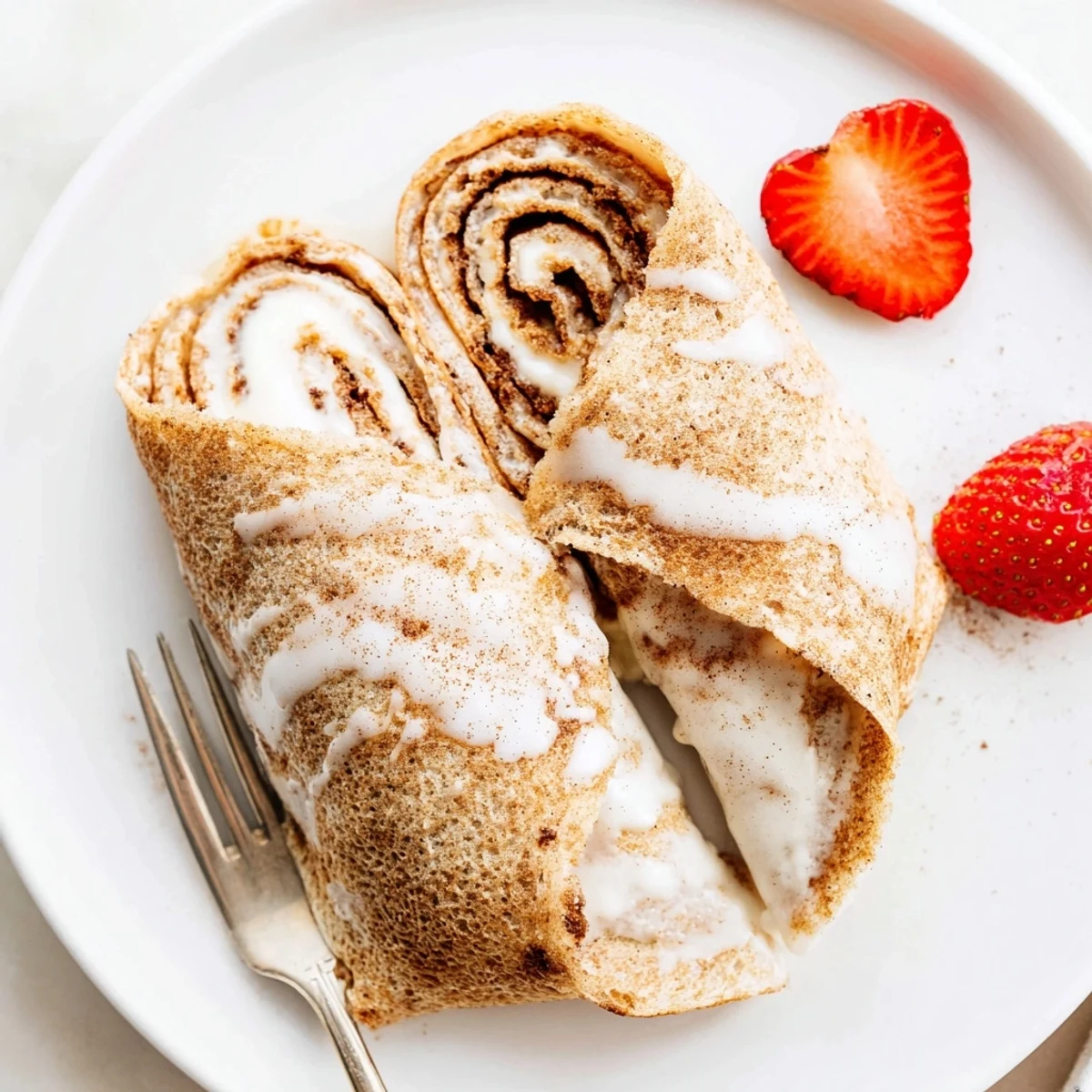 Lightly browned Cinnamon Roll Protein Crepes Recipe on plate, drizzle of maple