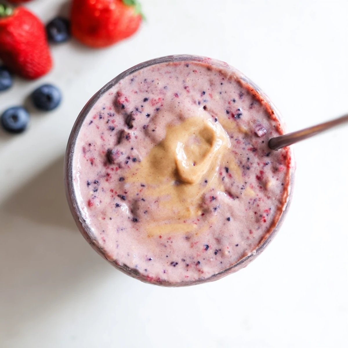 Creamy peanut butter berry smoothie poured into two tall glasses topped with fresh berries