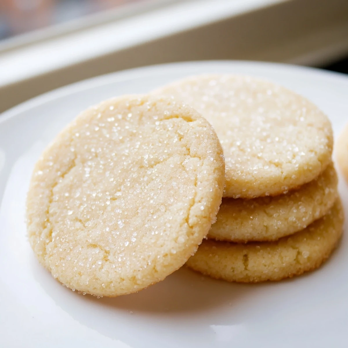Soft buttery sugar cookies dusted with sparkling sugar on a parchment sheet