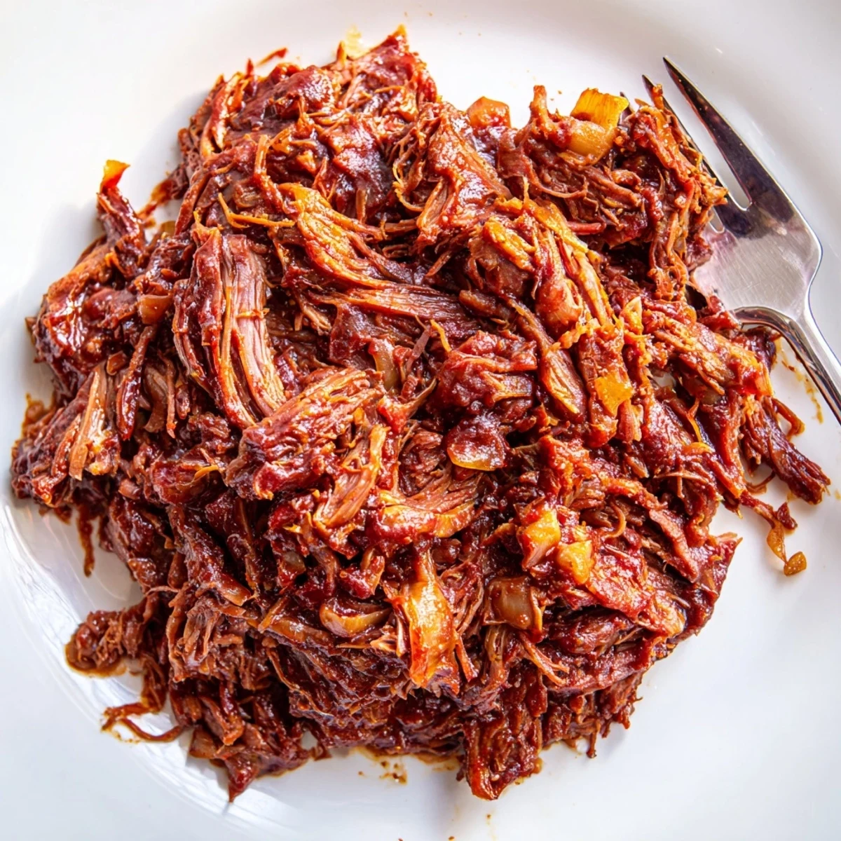 Tender Slow Cooker BBQ Pulled Beef shredded and glistening in rich smoky sauce