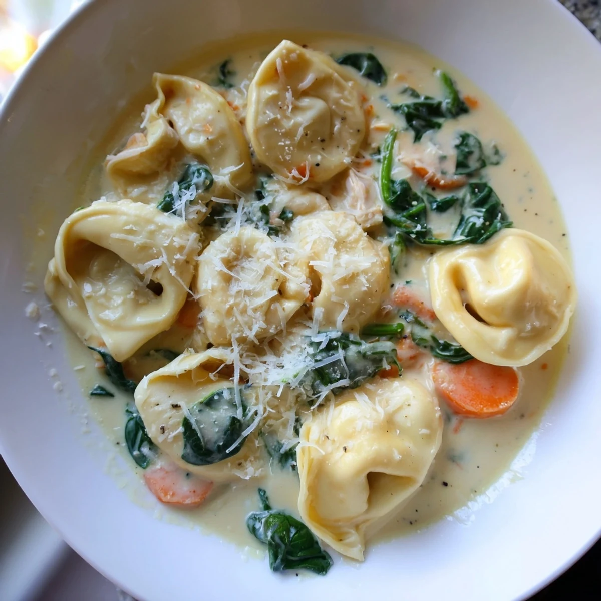 Creamy crockpot chicken tortellini in a golden broth with wilted spinach and tender carrots