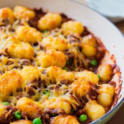 The Quick Gnocchi Shepherds Pie features a hearty beef filling with peas and carrots in a rustic skillet.