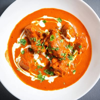 This bowl of homemade Butter Chicken features tender chicken pieces in a rich, spiced sauce, ready to be scooped up with naan.